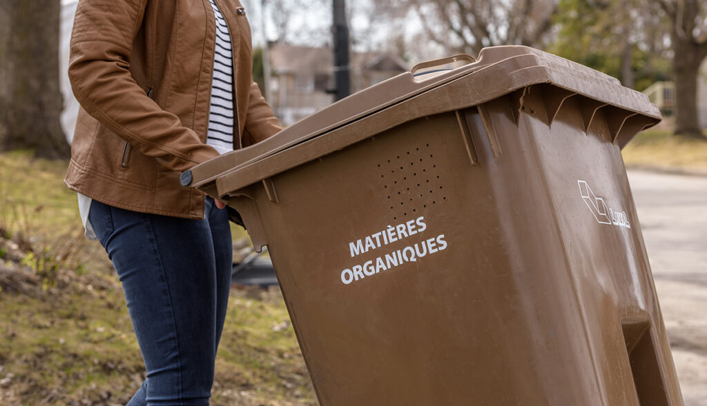 Une femme met son bac de compost au chemin